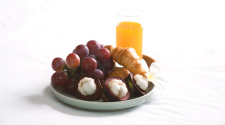 Breakfast, fruit, croissants, orange juice on a white bedsheet, Healthy food concept.の写真素材