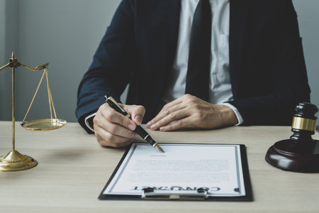 Lawyer hand holding pen and providing legal consult business dispute service at the office with justice scale and gavel hammer.の写真素材