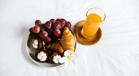 Breakfast, fruit, croissants, orange juice on a white bedsheet, Healthy food concept.の写真素材