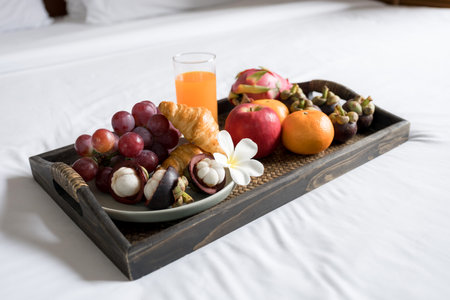 Breakfast, fruit, croissants, orange juice, in a black wooden tray, on a white bedsheet, Healthy food concept.の写真素材