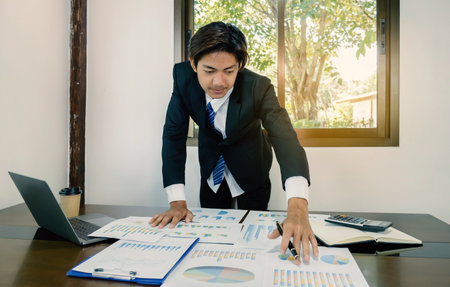 Businessman holding pen, analysis the graph with laptop at the home office for setting challenging business goals And planning to achieve the new targetの写真素材