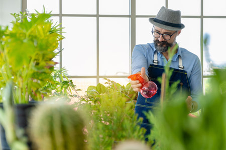 A senior man or grandfather with a mustache enjoys gardening for the tree at home after retirement.の写真素材