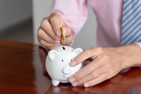 Businessman hand putting bitcoins into white piggybank. risk and wealth can happen in investment savings or trading in cryptocurrency innovationの写真素材