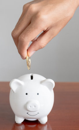 Businessman hand putting bitcoins into white piggybank. risk and wealth can happen in investment savings or trading in cryptocurrency innovationの写真素材