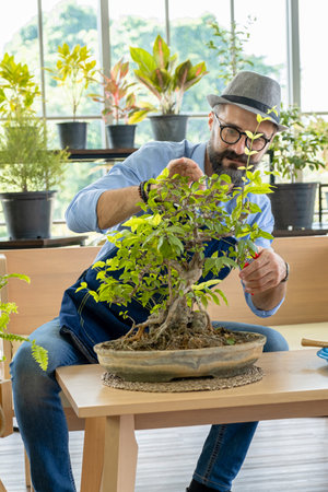 A senior man or grandfather with a mustache enjoys gardening for the tree at home after retirement.の写真素材