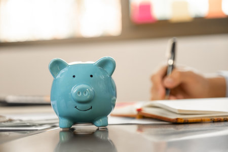Piggybank, Businessman hand writing income and expenses to account with dollar notes, step up start-up businesses to success, Saving money for future plan and retirement fund concept.の写真素材