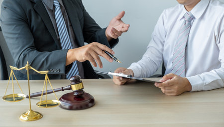 Lawyer hand holding pen and providing legal consult business dispute service at the office with justice scale and gavel hammer.の写真素材