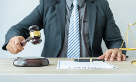Lawyer hand holding gavel hammer hit and providing legal consult business dispute service to the man at the office with justice scale.の写真素材