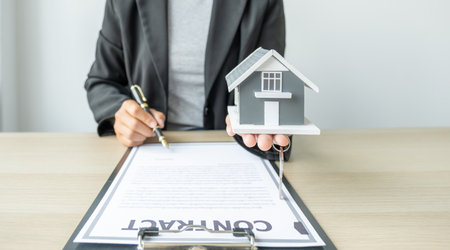 real estate agent hold the home model, sign and explain the business contract, rent, buy, mortgage, loan, or home insurance.の写真素材