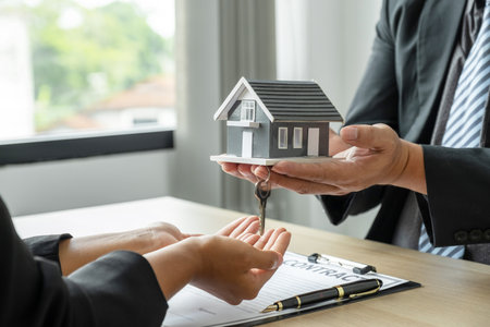 real estate agent hand hold the home model, and explain the business contract, rent, buy, mortgage, loan, or home insurance to the buyer woman.の写真素材