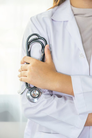 The female doctor held a stethoscope and stood in the ward with a folded arm.の写真素材