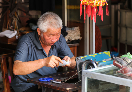 old man sewing in zhaoxin,guizhou,china