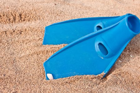 blue pair of flippers on hot sunny sandy beachの写真素材