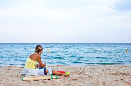 young blond woman on sandy beach watching the  waves の写真素材