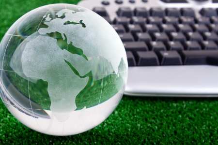 keyboard and glass globe on green grass