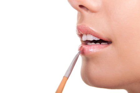 closeup of a woman applying lip gloss with brushの写真素材