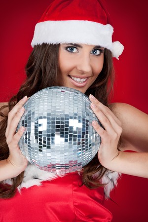 brunette woman in santa costume holding disco ball の写真素材