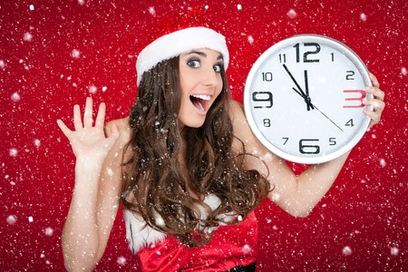 excited santa girl holding clock while snowing