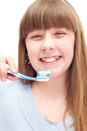 little girl brushing teeth with manual toothbrush, isolated on whiteの写真素材