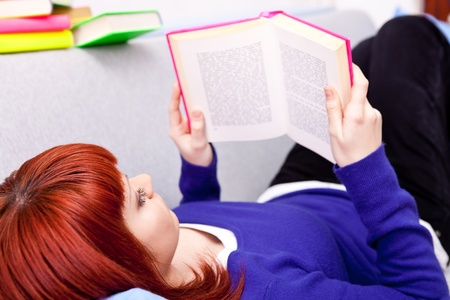 beautiful woman laying on bed and reading book の写真素材