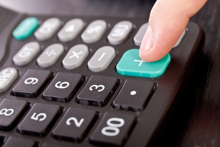 calculator with finger on button, close upの写真素材