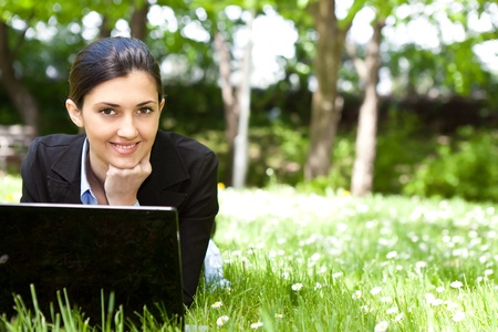smiling businesswoman using laptop in natureの写真素材