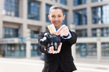 pretty businesswoman holding a piggy bank (focus on piggy bank)の写真素材