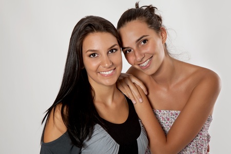 young sisters hugging on gray background, two smiling girlsの写真素材