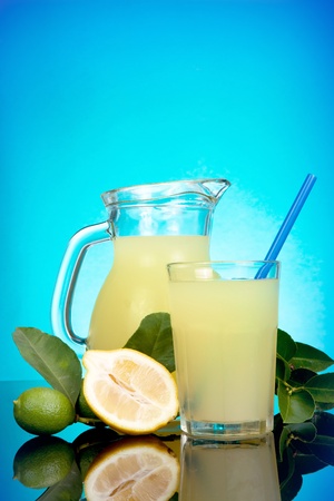 Pitcher of cool lemonade with glass on blue backgroundの写真素材