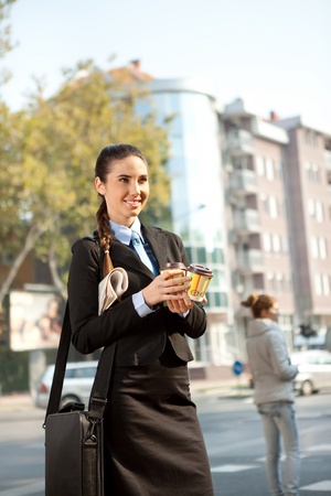 young businesswoman going to work with breakfast in hand, outdoorの写真素材