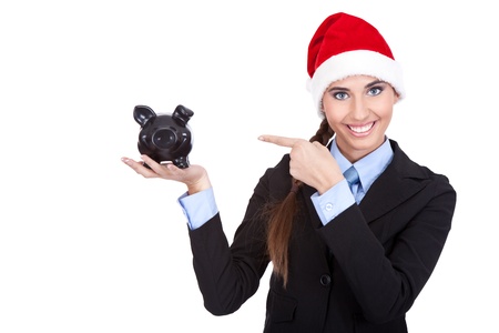 businesswoman with santa hat pointing in piggy bank, saving for christmasの写真素材