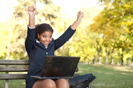 afro businesswoman with raised arms, success  with her workの写真素材