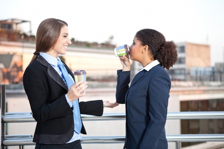 two young smiling businesswomen on coffee break, concept - time for coffeeの写真素材