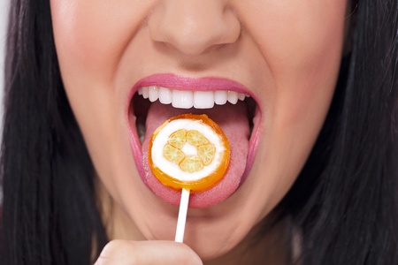 Young beautiful girl with lollipop in her mouth, close upの写真素材