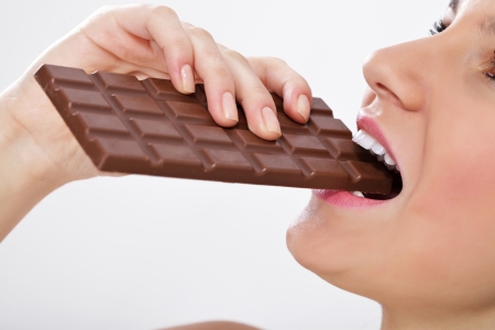 Closeup of smiling woman eating chocolate barの写真素材