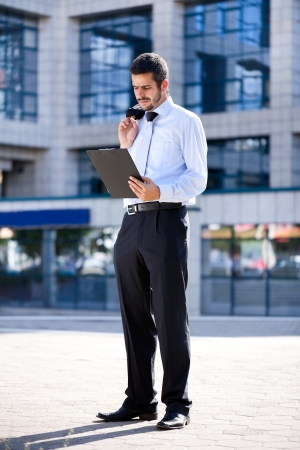 
Young businessman reading document outside a buildingの写真素材
