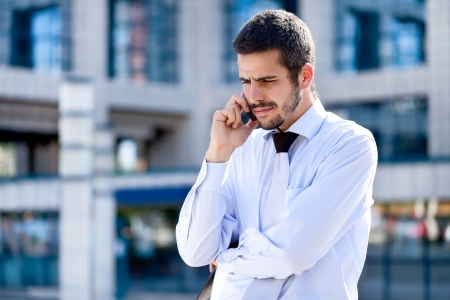 Businessman using a mobile phone standing outside a modern office buildingの写真素材