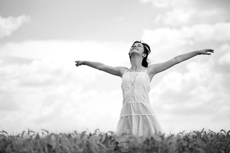 Young woman standing in wheat field, black and whiteの写真素材
