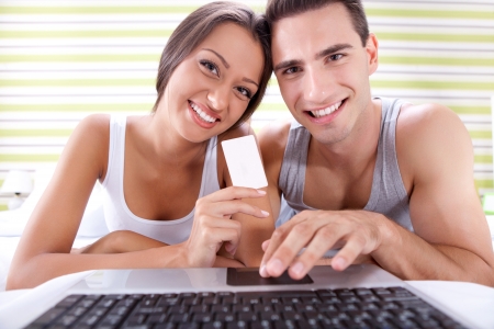 
Young smiling couple shopping online, lying in bedroom の写真素材