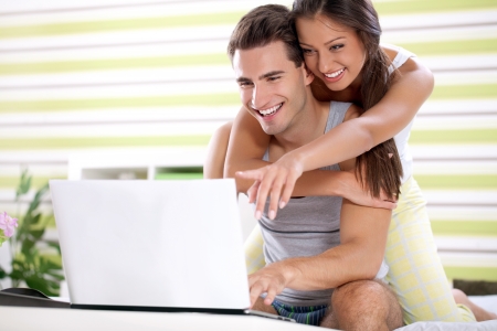 Young couple embracing and  together looking laptop, bedtime の写真素材