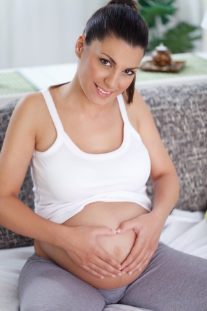 Young pregnant woman with heart shaped on her  bellyの写真素材