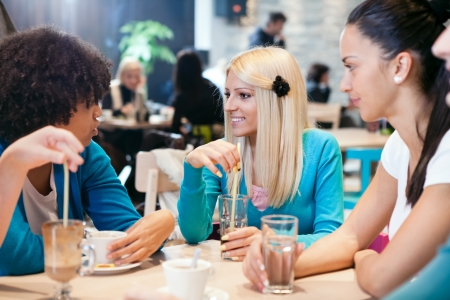 
Three young women drinking coffee in a cafeの写真素材