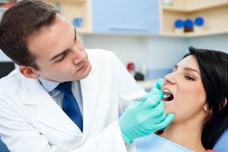 
young man dentist is treating teeth of the patientの写真素材