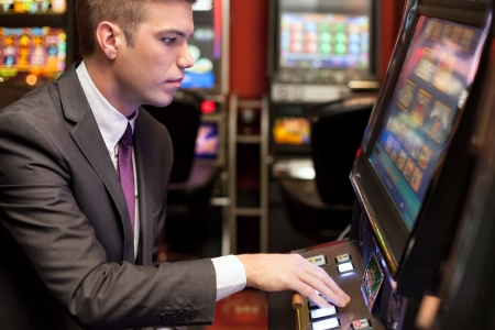 Young handsome men gambling in the casino on slot machinesの写真素材