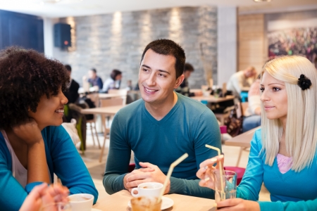 
Young man with his female friends sitting in cafe の写真素材