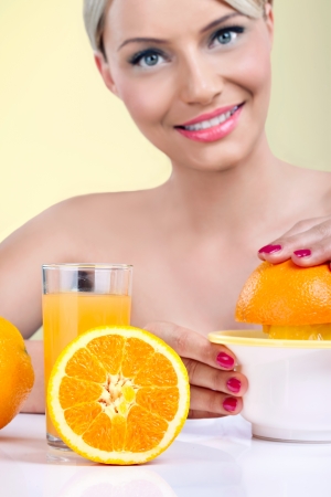 Beautiful woman making orange juice with fresh orange の写真素材