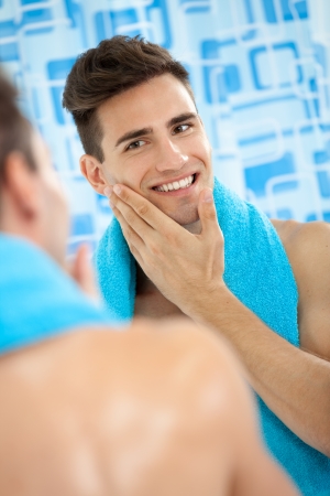 Young men touching his soft cheek after shavingの写真素材