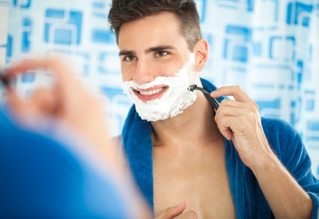 Sexy handsome young shaving and looking at himself in mirrorの写真素材