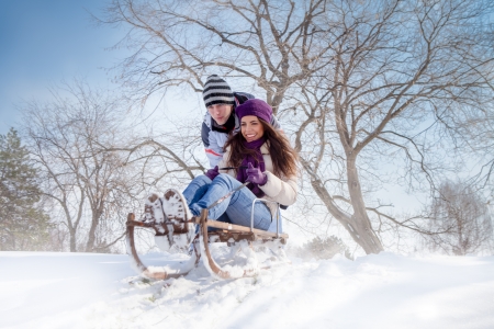 young couple having fun with sleigh outdoor, winter season 