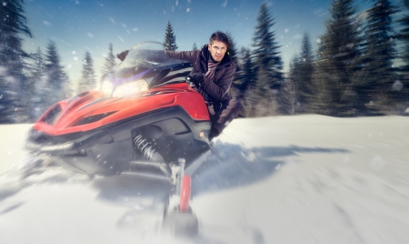 young man driving  snowmobile at beautiful winter day - in motion の写真素材